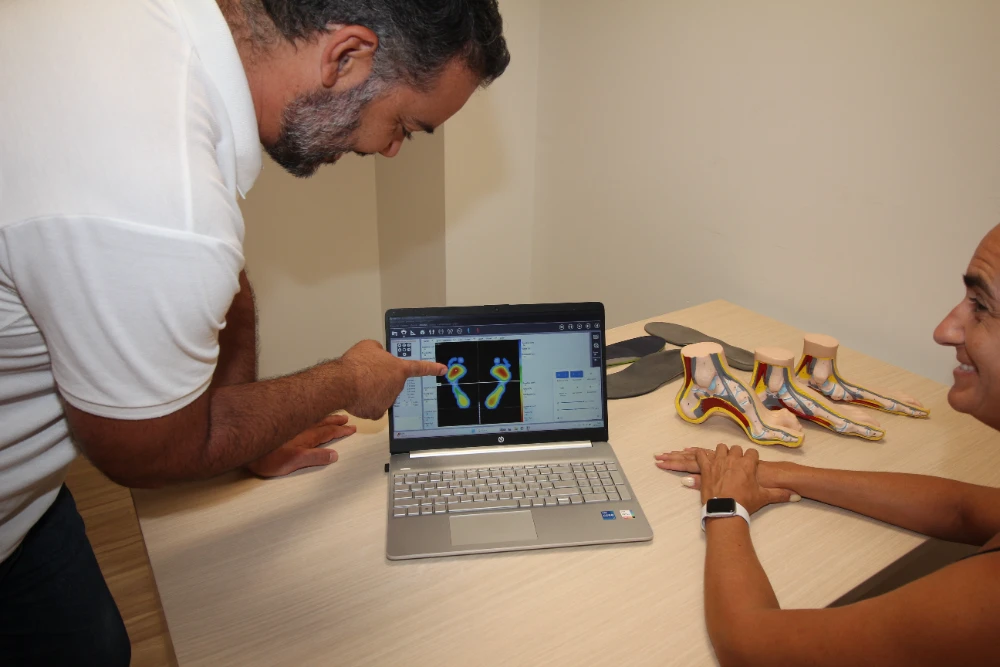 Podólogo explicando a una paciente un mapa de presiones plantares durante un estudio biomecánico de la pisada